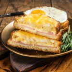 Croque monsieur and croque madame sandwiches with sliced ham, melted emmental cheese and egg