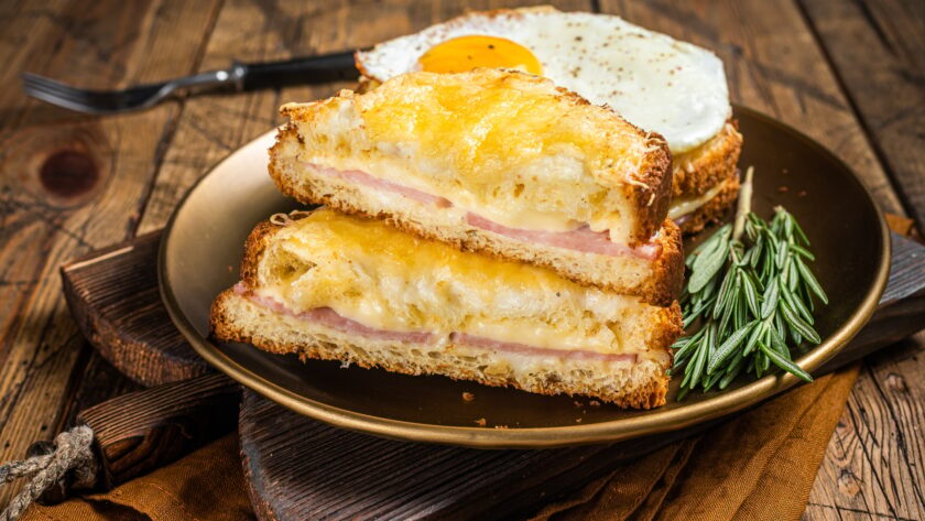 Croque monsieur and croque madame sandwiches with sliced ham, melted emmental cheese and egg