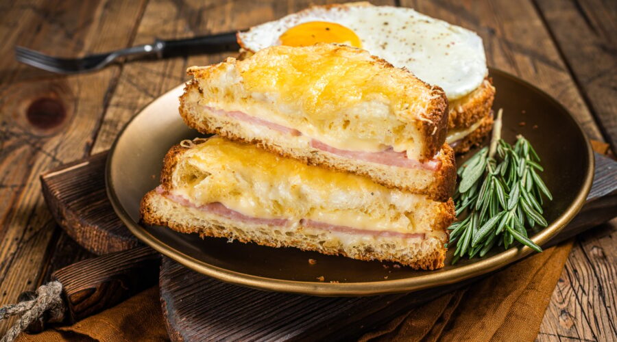 Croque monsieur and croque madame sandwiches with sliced ham, melted emmental cheese and egg