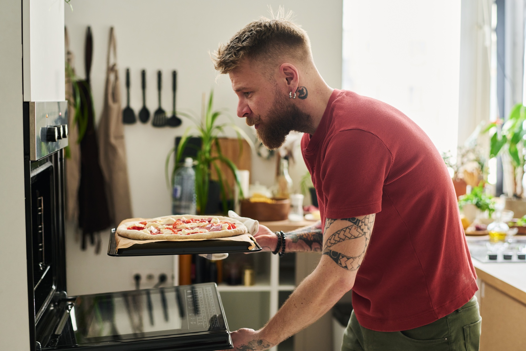 Man Putting Raw Pizza in Oven