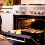 Young woman cooking cupcakes in the oven