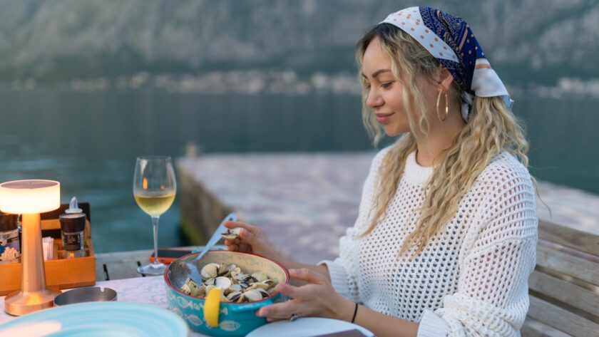 A woman eats mussels, a traditional Montenegrin dish, while sitting on the terrace of a restaurant