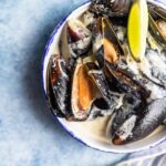 Blue mussels in wine sauce with lime and bread. Stew mussels in wine, leek and blue cheese. Seafood