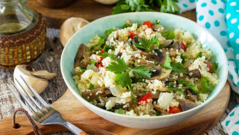 Diet food vegan concept. Vegan salad with couscous and champignons on a wooden table.