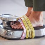 Diet, weight loss and feet of a woman on a scale for body check, measure and balance to lose weight