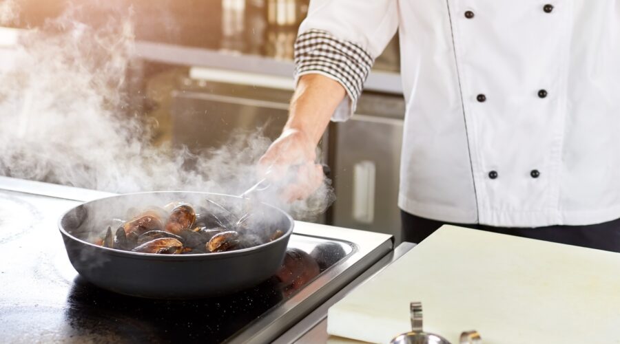 Shellfish mussels cooking in pan.